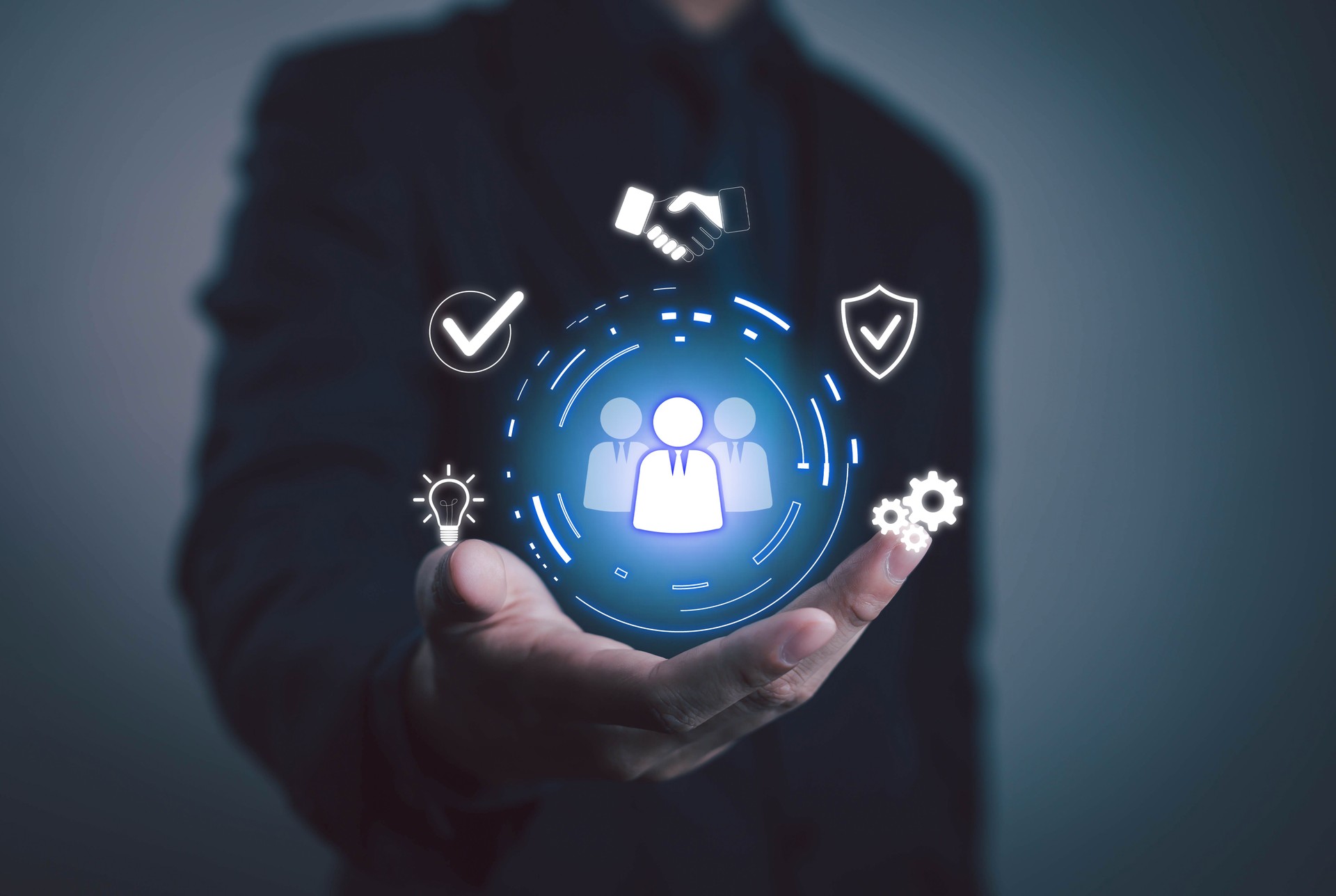 Businessman holding digital hologram of human resources icon. Teamwork, innovation, technology and leadership concept for success and strategy of modern organization. Consulting, HR company.